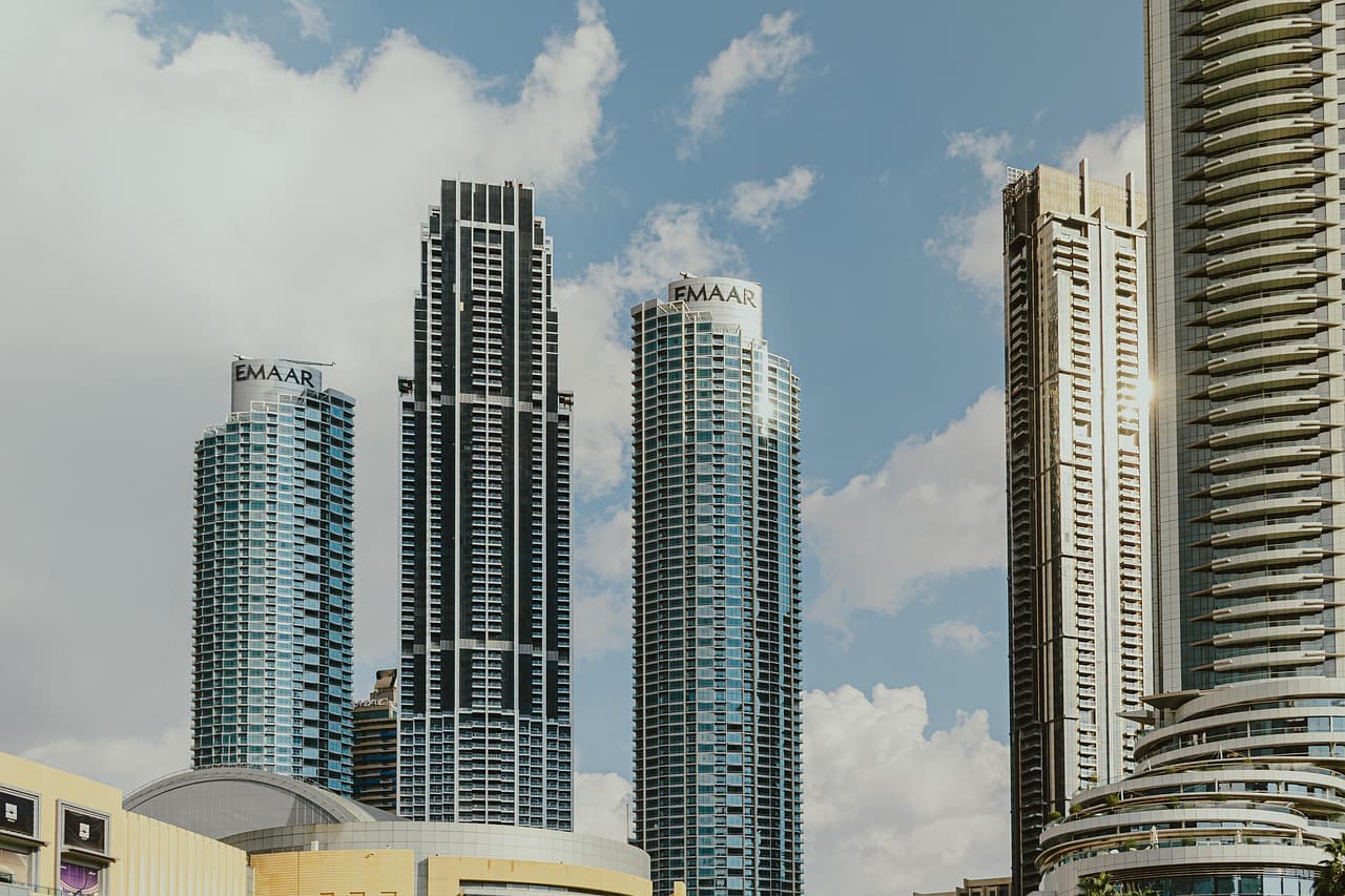 High-rise residential towers in Downtown Dubai against a blue sky with scattered cloud