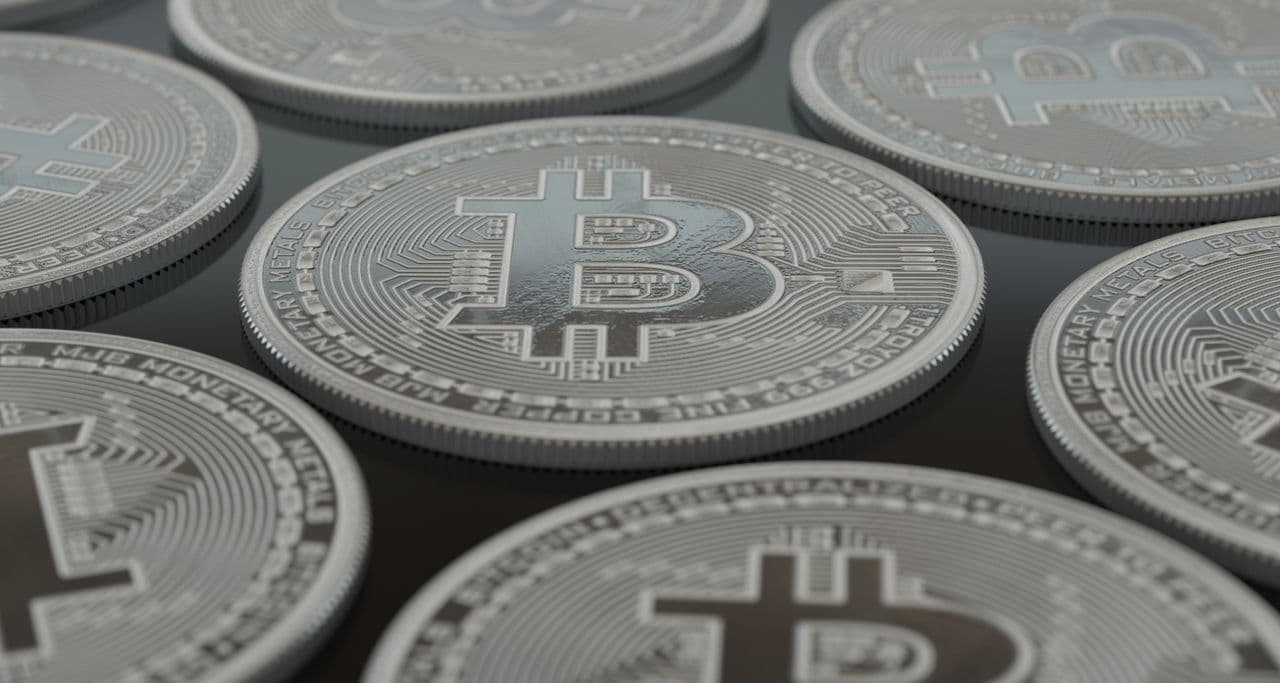 Close-up of silver physical Bitcoin coins arranged on a dark surface